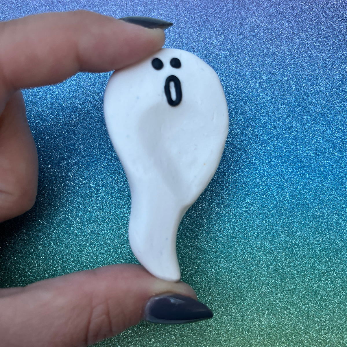 Polymer Clay Geist Worry Stone auf glitzerndem Hintergrund